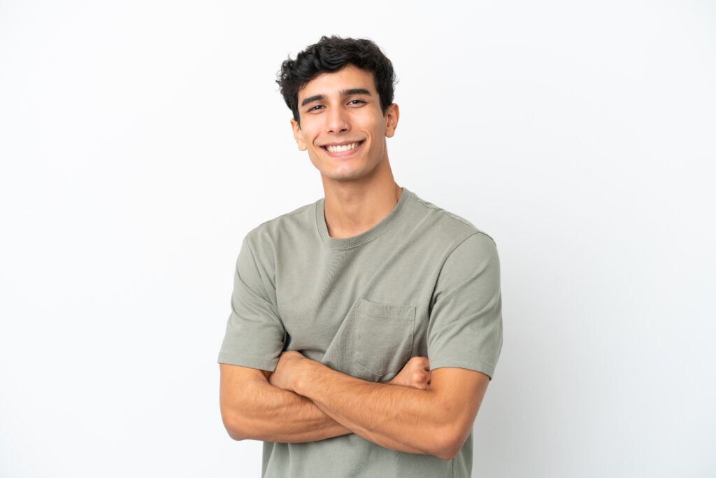 young argentinian man isolated on white background with arms crossed and looking forward